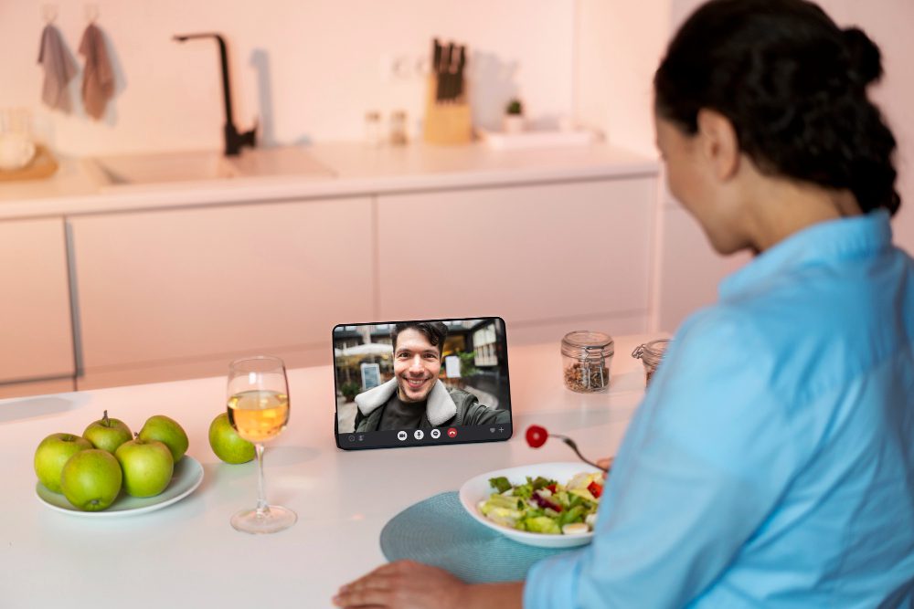 Person having a video call at a kitchen table with food and drink nearby